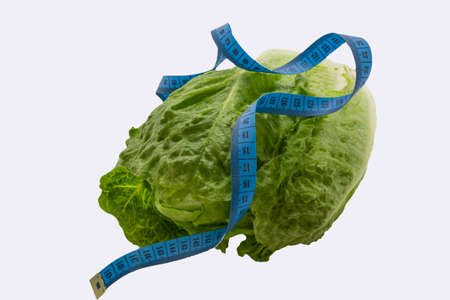 measuring tape on green Romaine lettuce isolated on white. Healthy vegetarian, organic food, diet, weight loss concept, horizontal, copy spaceの写真素材