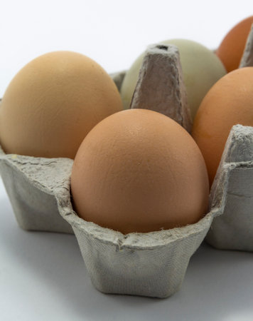 chicken eggs in a carton box on white background. Easter holiday eggs natural colour background,...