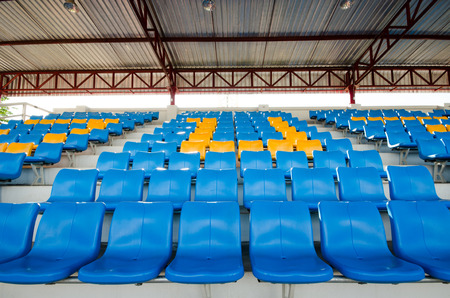 Empty plastic chairs of blue and yellow  on grandstand stadium