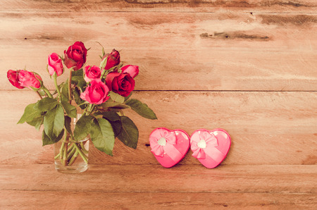 Red roses in glass and Heart shaped Valentine's Day gift box on wooden background.の写真素材