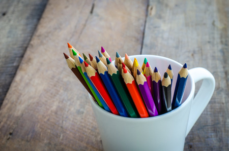 Stack of colored pencils in a glass on wooden backgroundの写真素材