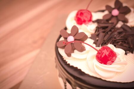 Birthday cake, vanilla Chocolate Cherry was divided pieces on a wooden tableの写真素材