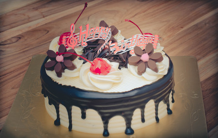 Birthday cake, vanilla Chocolate Cherry was divided pieces on a wooden tableの写真素材