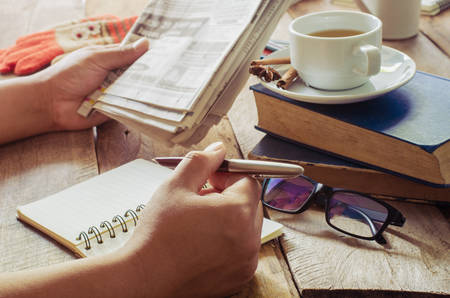 Hand holding a pen and paper and tea on the desk in the morning.の写真素材