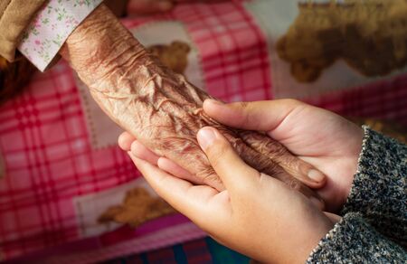 Girl's hand holding old woman show love and concern.の写真素材