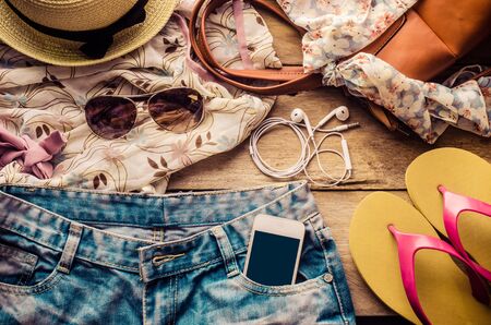 accessories for teenage girl on her vacation, hat, stylish for summer sunglasses, leather bag, sneakers and costume on wooden floor.の写真素材