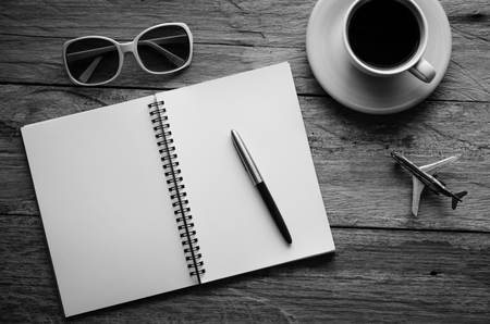Notebook pen and cup of coffee on wood - tone black and whiteの写真素材
