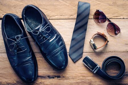 Leather shoes and accessories for work lay on the wooden floorの写真素材