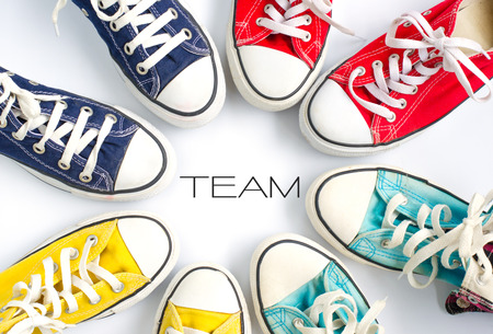 Multicolored sneakers on white background and word TEAM concept team work