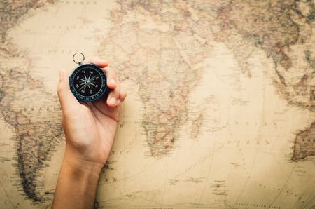 Tourists hold a compass and locate a place on a world map.の写真素材
