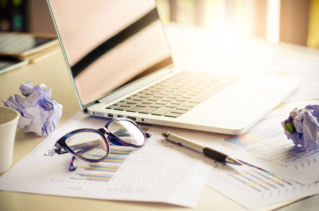 glasses on office desk and office supplies.office desk table with a laptop and analyzing investment chart.の写真素材