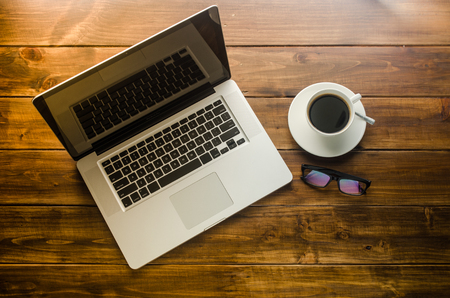 Laptop and cup coffee on wooden floorの写真素材
