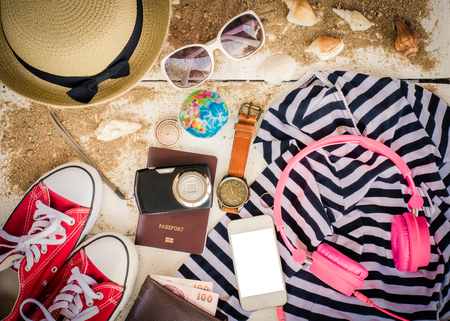 Travel accessories, hats, sunglasses, notebook, pen, phone, shell, placed on a wooden floorの写真素材