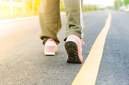Woman jogging on road close up on shoes in the eveningの写真素材