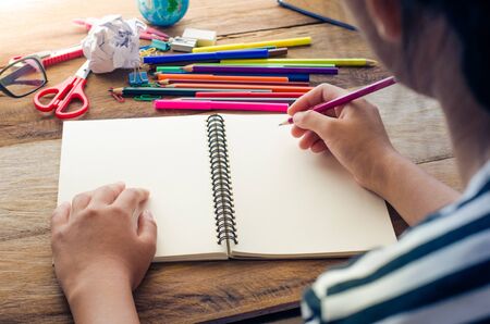 Behind the girls were sitting down to write something on the books and school supplies placed in...
