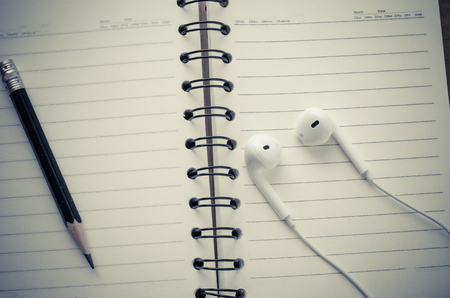 The notebook is turned on and a pencil with headphonesの写真素材