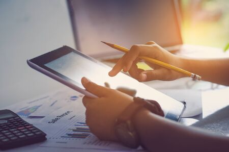 Businessman holding Tablet and working with laptop on the table and analyzing investment chart working in office. Business work concept.の写真素材