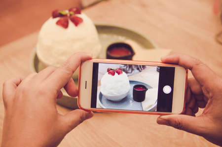 People using smartphones take photo sitting at the cafe comfortableの写真素材