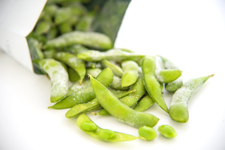 Green beans pour out of the bag on a white backgroundの写真素材