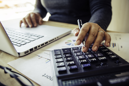 Business women are using a calculator to calculate the income of the business.の写真素材