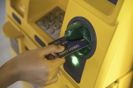 Hand inserting with a credit card into bank machine . Man using an atm machine with  credit card to withdraw moneyの写真素材