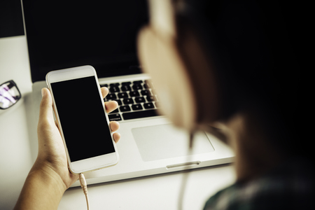 People are using a smartphone to listen to music and wear headphones.の写真素材