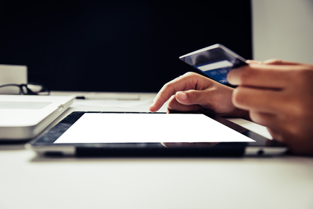 Hand holding a credit card in their hands and find information about a product using their mobile device to make purchases online and conduct financial transactions.の写真素材