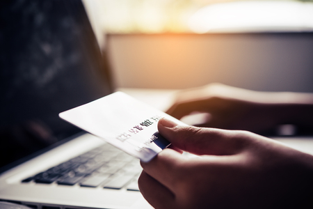 Hand holding a credit card in their hands and find information about a product using their mobile device to make purchases online and conduct financial transactions.の写真素材