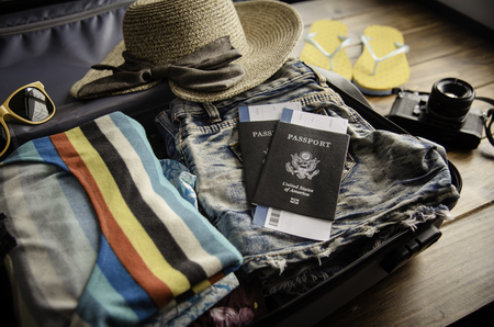 Clothing traveler's Passport, wallet, glasses, smart phone devices, on a wooden floor in the luggage ready to travel.の写真素材