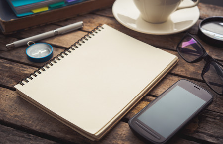 Office table with blank notebook and smartphone / Coffee cupの写真素材