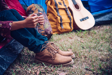Young woman holding a glass of drink sitting in a tent in the morning nature.の写真素材