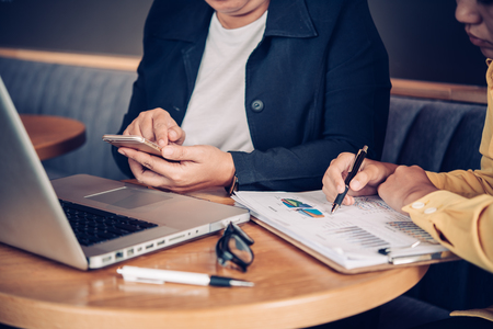 Businessmen working with laptop and smartphone in open space office. Meeting report in progressの写真素材
