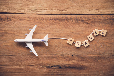 Airplane with the text Travel placed on a wooden floor. Travel ideas