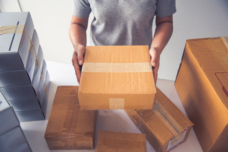 Hand holding closed-up tapes to pack products to prepare shipments.の写真素材