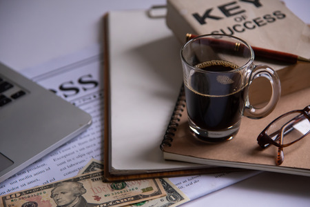 Black coffee and dollar is placed on a desk with office equipment and placed.の写真素材