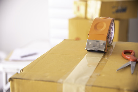 The staff is using the tape to pack the package goods to the customer.