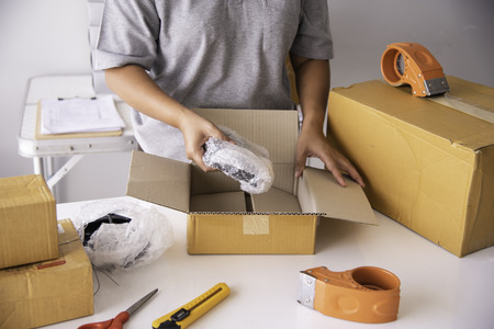 The staff is using the tape to pack the package goods to the customer.