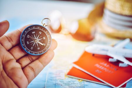 Tourists hold a compass and locate a place on a world map.の写真素材