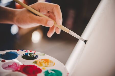 close up girl holding pallet and drawing on canvas using paints の写真素材