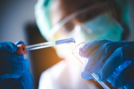 closeup-pipette dropping a sample into a test tube in an experiment research in laboratory.の写真素材