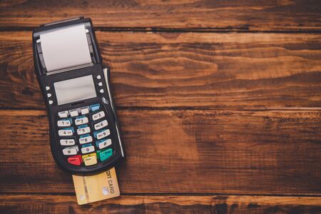 Top view credit card swipe machine placed on a wooden floor , Meaning payment by credit card