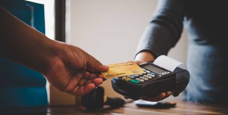 Close up of hand using credit card to pay by sending the credit card to the staff at the credit card swipe machine. Online paymentの写真素材