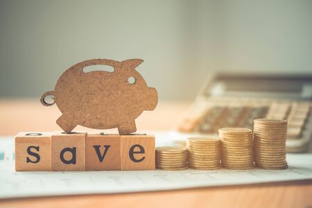 The coins are stacked and wooden blocks are pig on the wooden floor. - Savings ideas for increasing volume.の写真素材