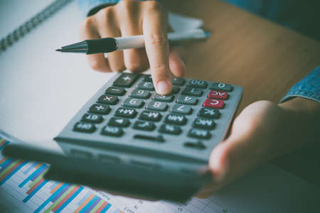The accountant's hand is using the calculator. For cost analysis Profit and loss and tax calculation...