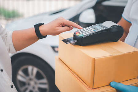 Male delivery workers wear sanitation faces and wear gloves, deliver goods or parcels, delivery service for users to pay via credit card for convenience and forgiveness during covid19.の写真素材