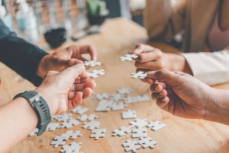 Business team handle a piece of white puzzles that are about to drop to get a complete worksheet -...