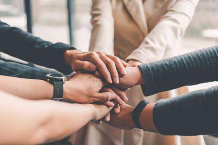 Hands of business people come together in a stack of hands to symbolize collaboration, teamwork to...