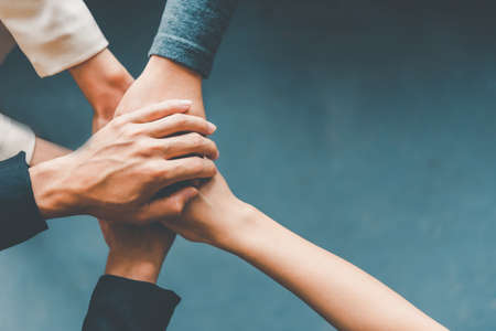 Top view hands of business people come together in a stack of hands to symbolize collaboration,...