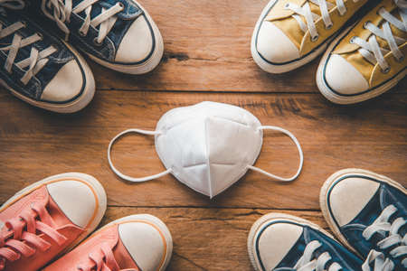 protective mask is placed on a wooden floor with shoes placed around it. Concept new normal...