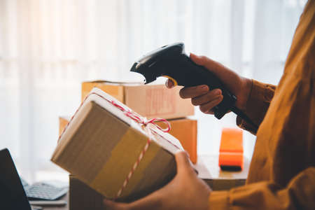 Delivery staff scanning cardboard box with barcode scanner to check products for customersの写真素材